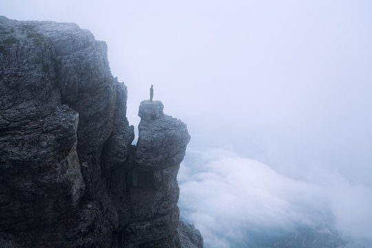 Male hiker standing on top of mountain cliff