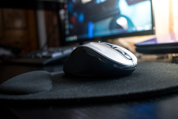 Closeup of Wireless Bluetooth computer mouse on a black desk with mouse pad in home studio