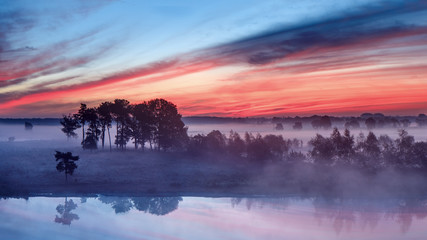 Tranquil wet land at a colorful daybreak with dramatic clouds, Turnhout, Belgium