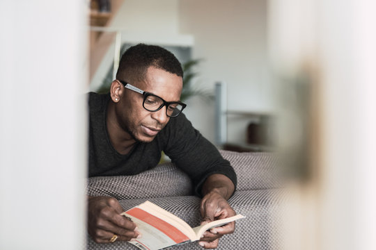 Handsome adult man reading book at home