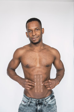 Crop black shirtless man with bar of chocolate