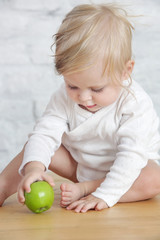 Fototapeta premium Baby eat an organic green apple - fresh apple as perfect healthy finger food for little ones