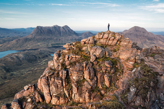 Person standing on top of a large mountain