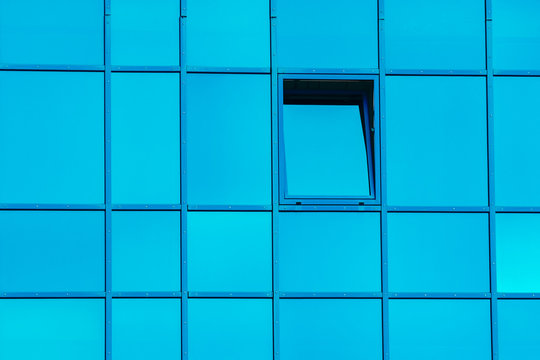 part of a building with blue windows with an open window