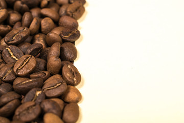Scattered roasted coffee beans on beige background