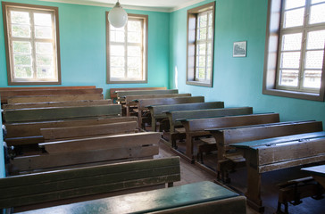 Altes Klassenzimmer einer Schule mit Holzbänken und Holztischen