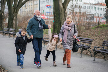 Grandparents having fun with their grandchildren in city park. - obrazy, fototapety, plakaty
