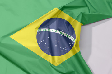 Brazil fabric flag crepe and crease with white space, green yellow and blue color and world in center.