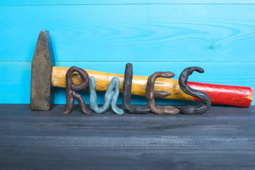 Breaking the rules concept, plasticine letters and a hammer on the blue background.