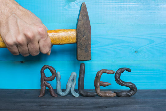 Breaking The Rules Concept, Plasticine Letters And A Hammer On The Blue Background.