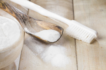 baking soda in bowl on wooden table, close up