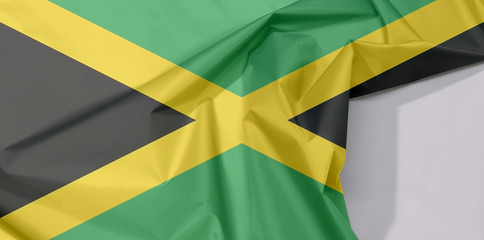 Jamaica fabric flag crepe and crease with white space, A gold diagonal cross divides the field into four triangles of green and black.