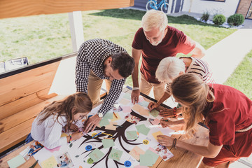 Pleasant interaction. Concentrated little girl bowing head while doing her family tree