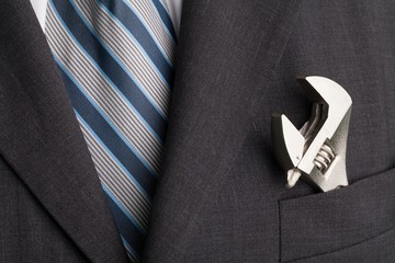 Man wearing a suit with an adjustable wrench in the front pocket