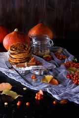 Autumn concept. Pumpkin pancakes with caramel topping, with pumpkins, leaves on a dark background.