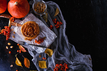 Autumn concept. Pumpkin pancakes with caramel topping, with pumpkins, leaves on a dark background.