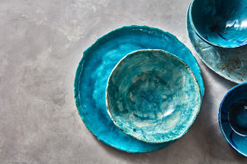 Porcelain blue bowls and plates on a gray table . Colorful ceramic vintage handmade dishes. Flat lay