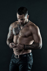 Fototapeta na wymiar My cell phone is my best friend. Man with tattoo on muscular body. Muscular man use mobile phone. Tattoo and body art. Sport is all about playing and competing