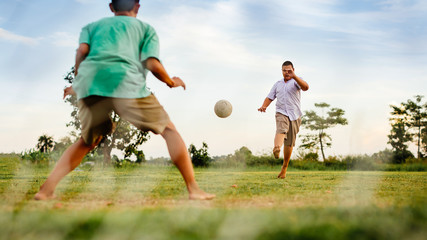Fototapeta premium An action picture of a group of kid playing soccer football for exercise in community rural area under the sunset.