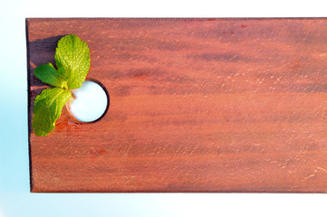 branch of mint on a brown wooden board illuminated by the sun at sunset