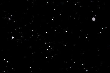 Snowstorm texture. Bokeh lights on black background, shot of flying snowflakes in the air