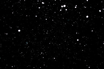 Snowstorm texture. Bokeh lights on black background, shot of flying snowflakes in the air