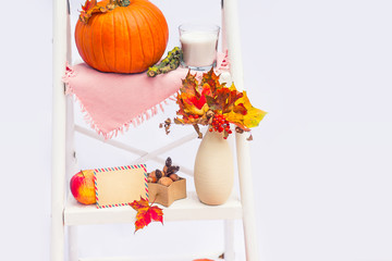 Cosy composition with natural decor of pumpkin, candle, fall leaves in vase, blank postcard on the...