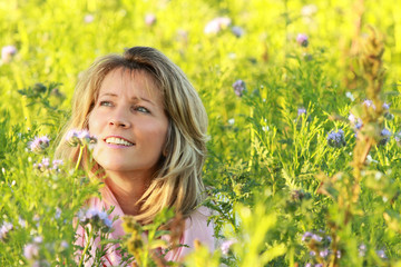 Happy mature woman enjoys leisure time in a flowerfield