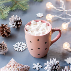 Fototapeta na wymiar Winter background with hot drink with marshmallows, Christmas lights, fir tree and decorations.