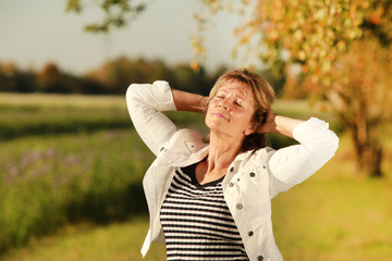 Happy middle age woman taking a sunbath in autumn