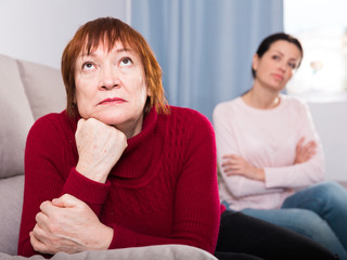 Unhappy women sitting at sofa after conflict at home