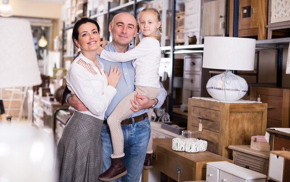 Couple with small girl standing in furniture shop