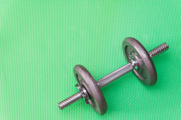 gray weights and dumbbells for sports on a green background