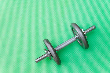 gray dumbbell with disks on a green background