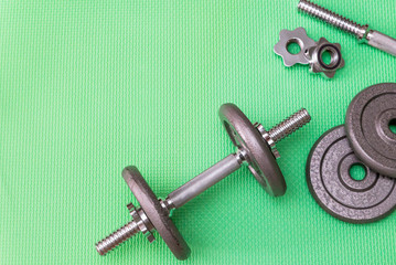 metal dumbbells for sports on a green background, gray weights