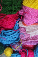Big piles of knitted colorful patches and balls of yarn. 