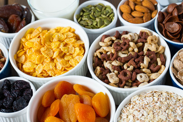 various cereals, nuts and dried fruits on wooden surface
