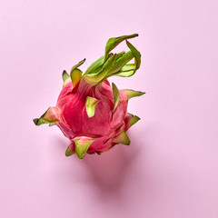 View from above to tropical fruit - pitahaya with green leaf on a pink background, copy space. Top...