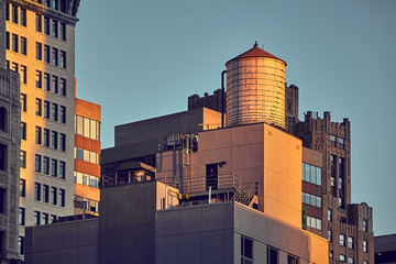 Vintage toned picture of water tank on rooftop at sunset, New York City, USA.