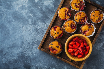 Strawberry chocolate cupcakes muffins on old wooden stand on concrete gray background. Top view.