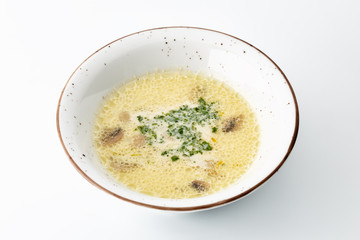 cream soup with greens in a large white plate isolated on white background