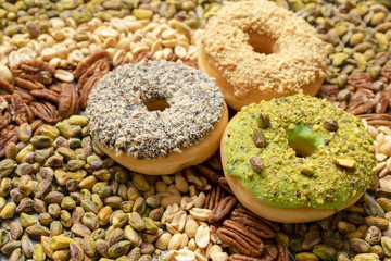 Set of three American doughnuts on pecan nuts, pistachios and peanuts. Candy shop concept. 