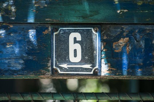 Weathered grunge square metal enameled plate of number of street address with number 6 closeup