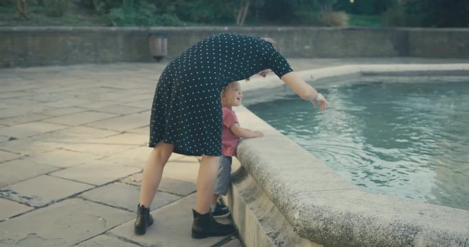 Yougn woman and toddler playing by a fountain