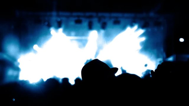 A blank space appears progressively on a stage under spotlights - useful for titling or incrustations - Shapes of a crowd in a foreground.