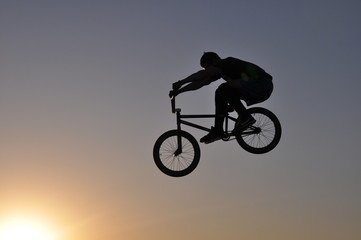 silhouette of cyclist on a white background of blue sky
