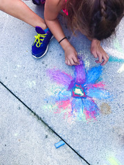 child playing with chalk on asphalt