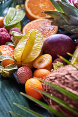 Summer exotic fruits - carambola, pineapple, coconut, mango, kiwi, halves of orange on a green...
