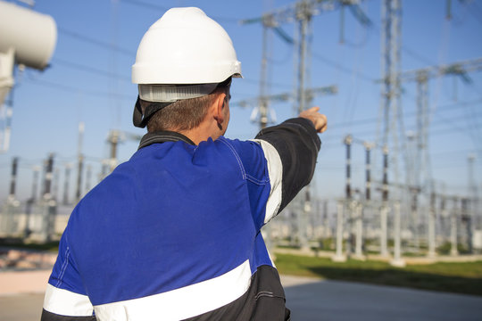 Electrician engineer on power electric station point to high voltage equipment
