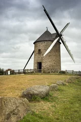 stones and old wind mill on meadow in France